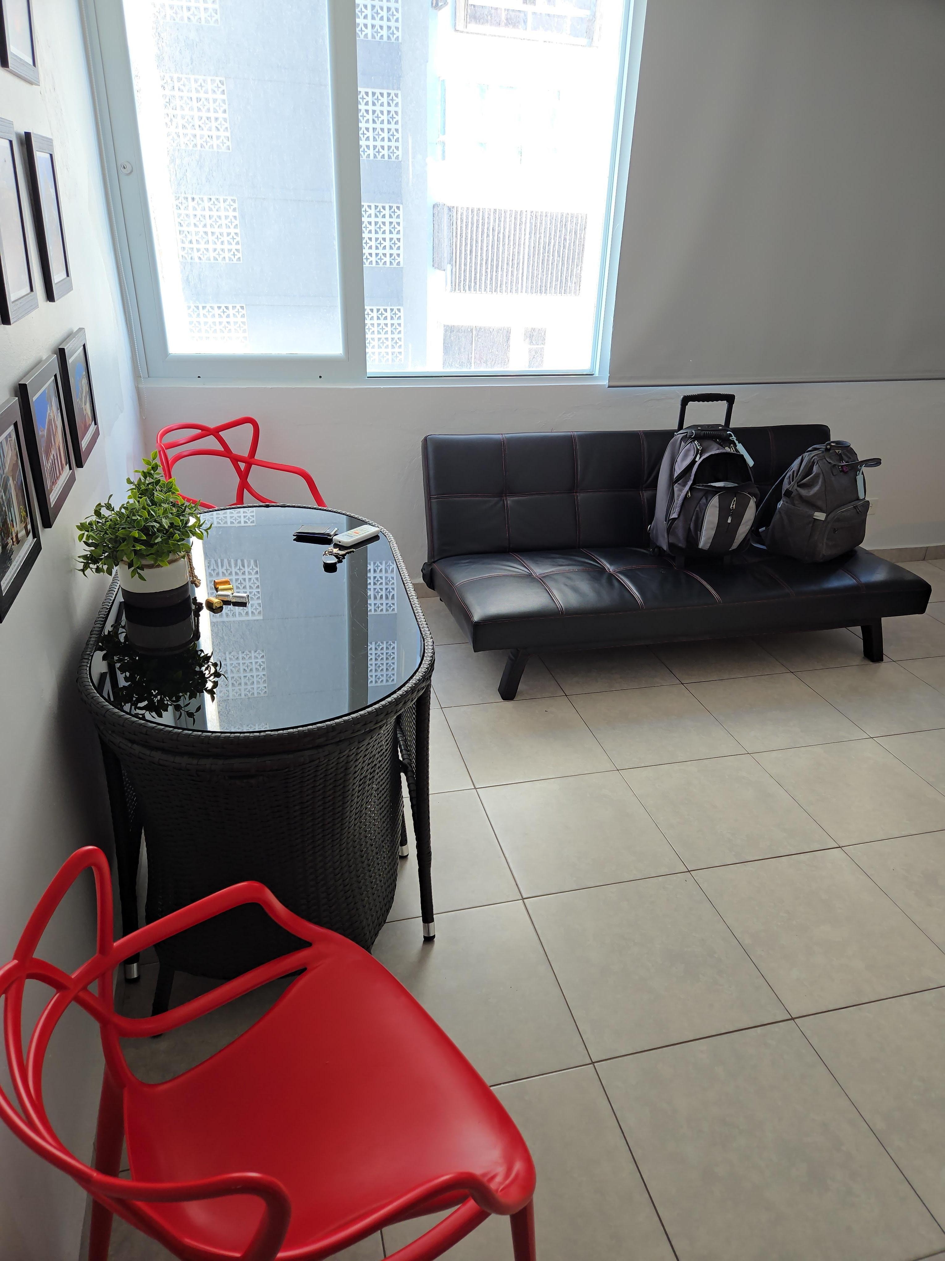 Dining table, futon couch and 2 red chairs