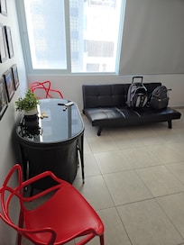 Dining table, futon couch and 2 red chairs