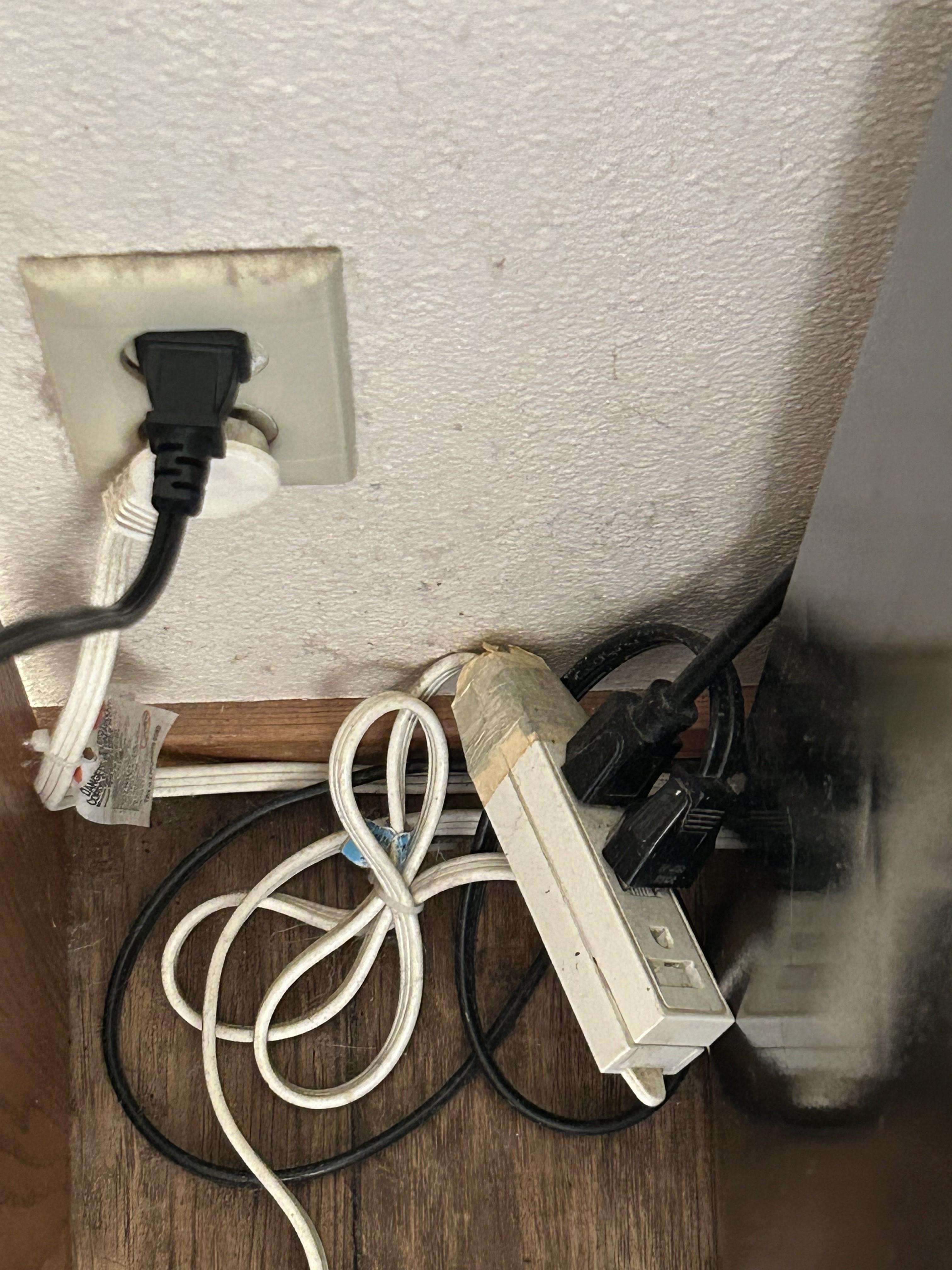 Grimy outlet, dirty floor and cords.