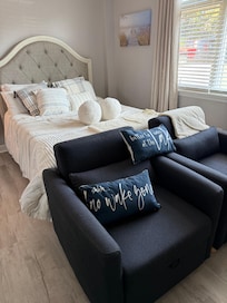 The bedroom with two chairs in front of the TV and fireplace