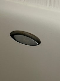 Drain plate cover behind the tub, leaving an open gap.