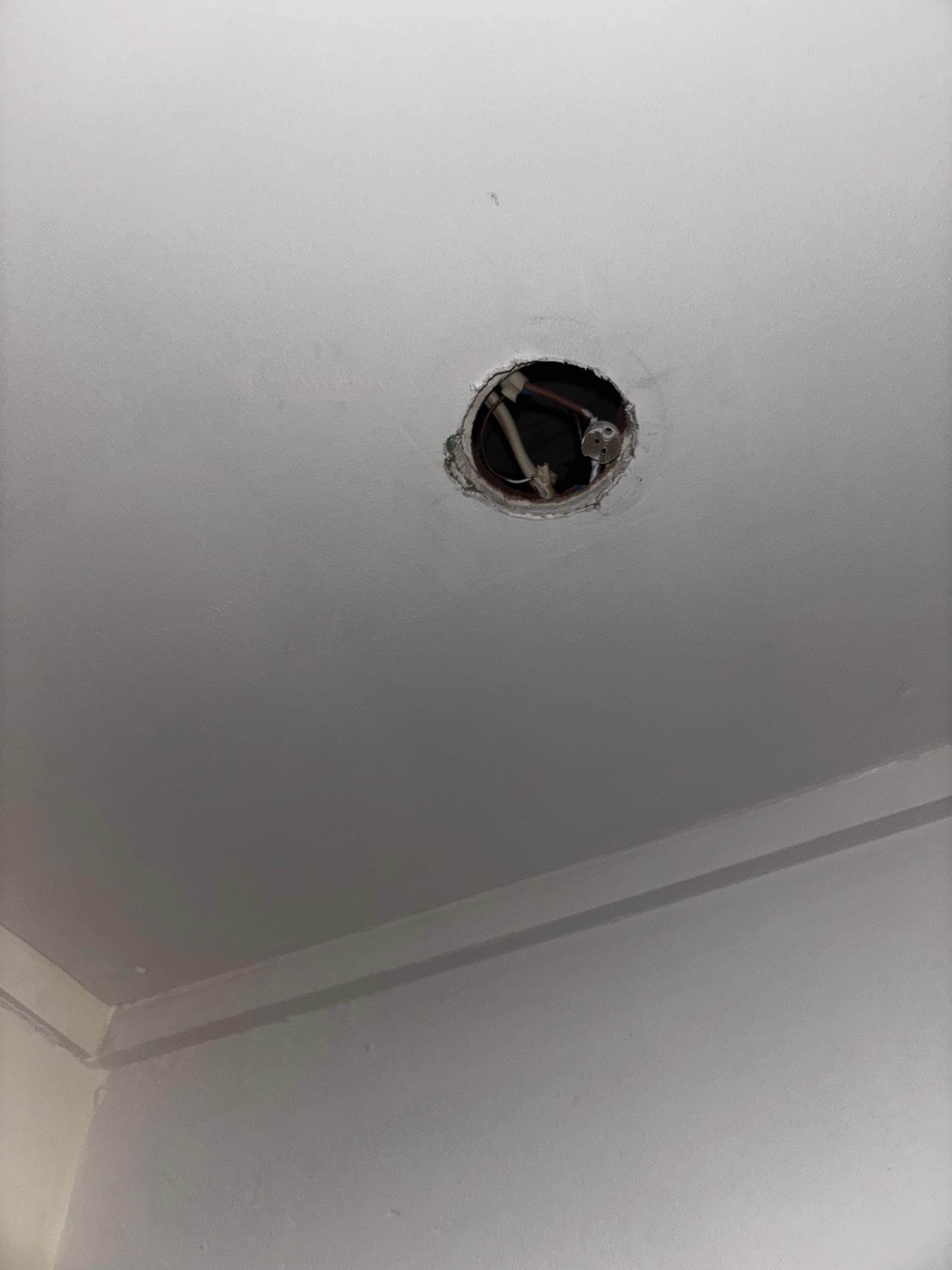 Broken light fixture with the wires slightly exposed.