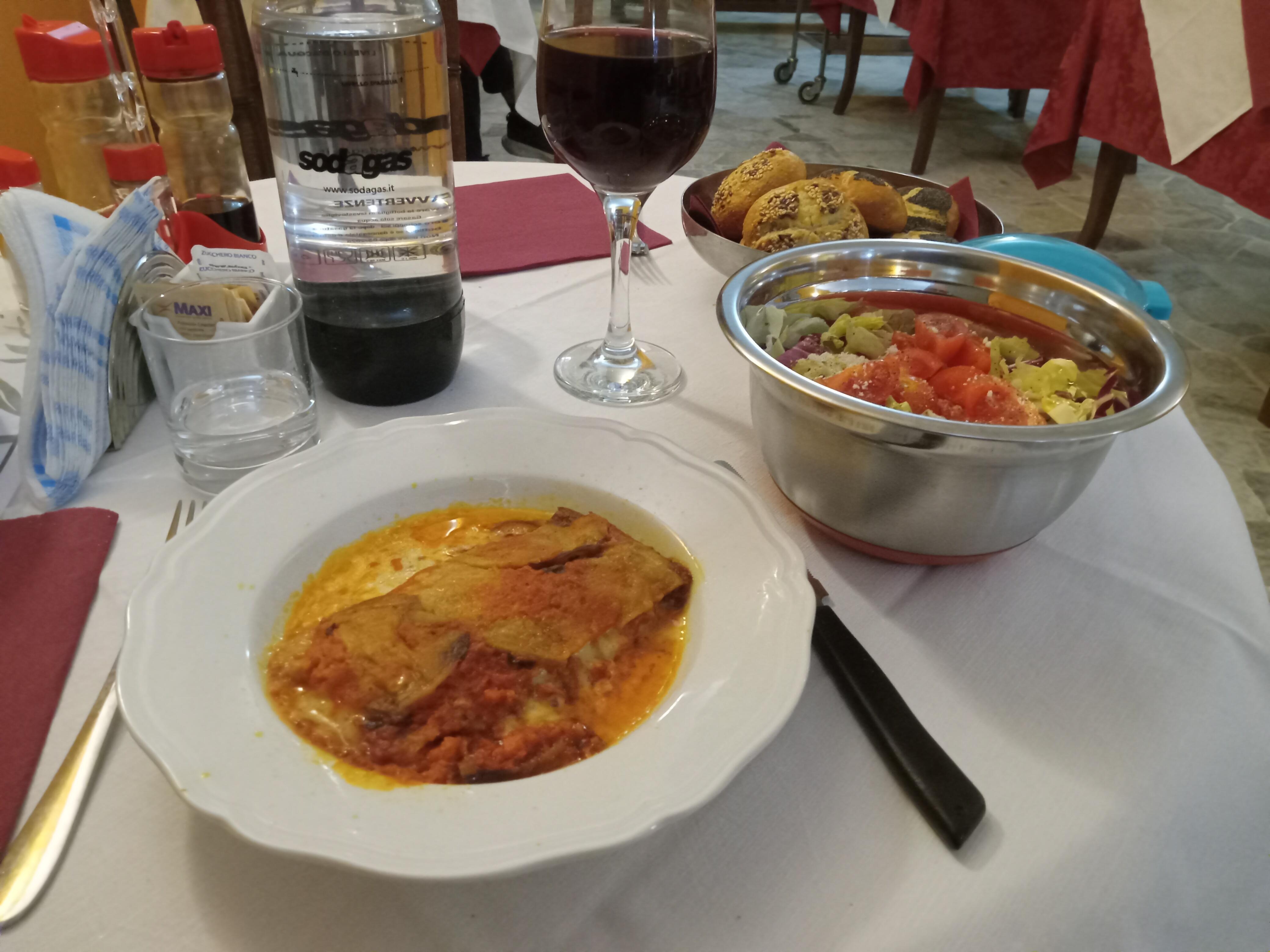 Eggplant parmigiana, mixed salad, and a glass of wine