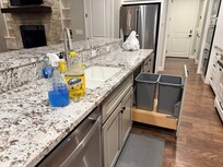 bag of trash and cleaning supplies left on kitchen counter