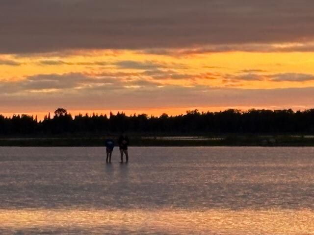 The Boys walking out in the water at sunset.