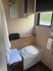 Chemical toilet with window looking onto road and parking area