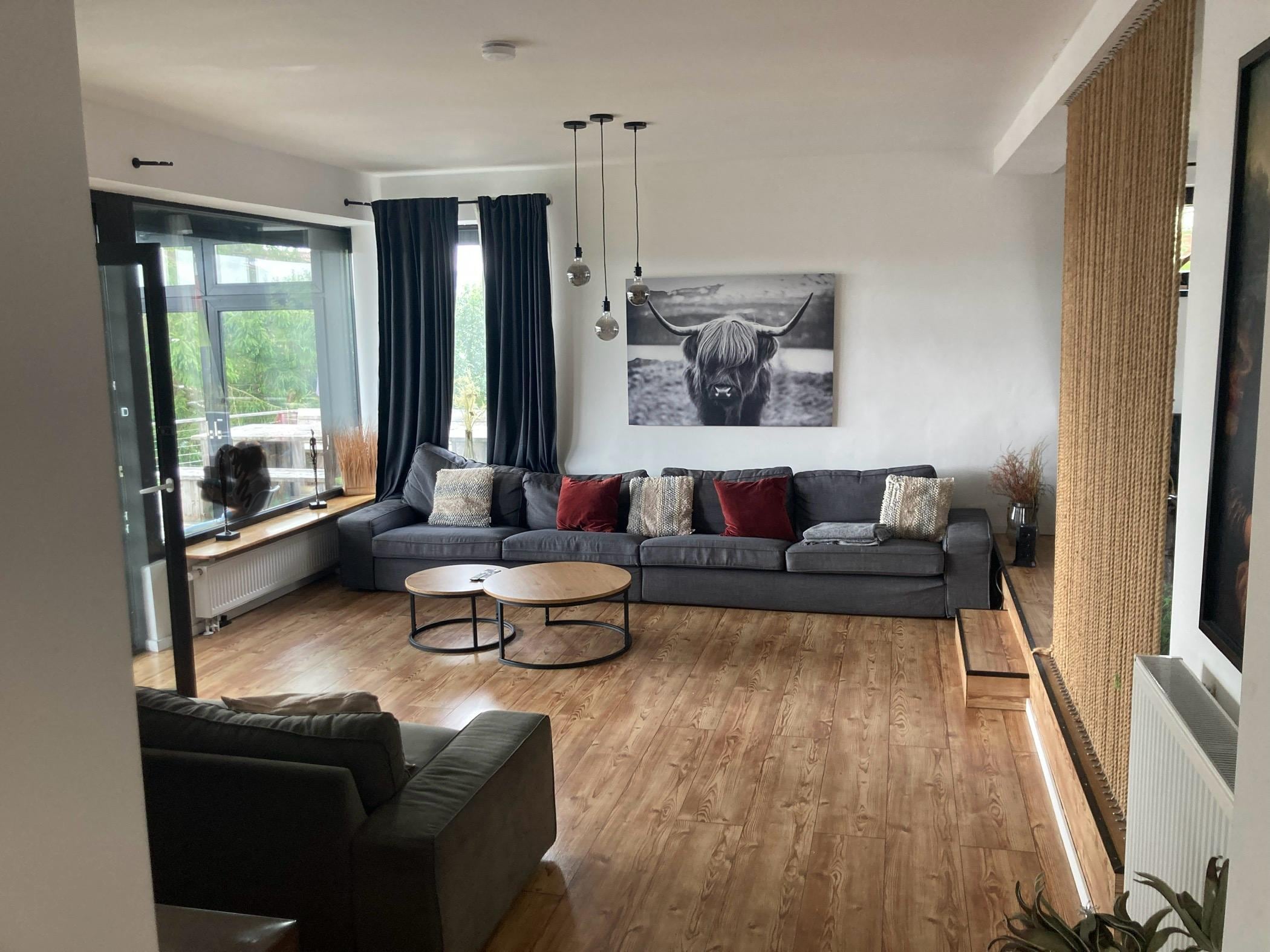 Ruime woonkamer met links een groot tv