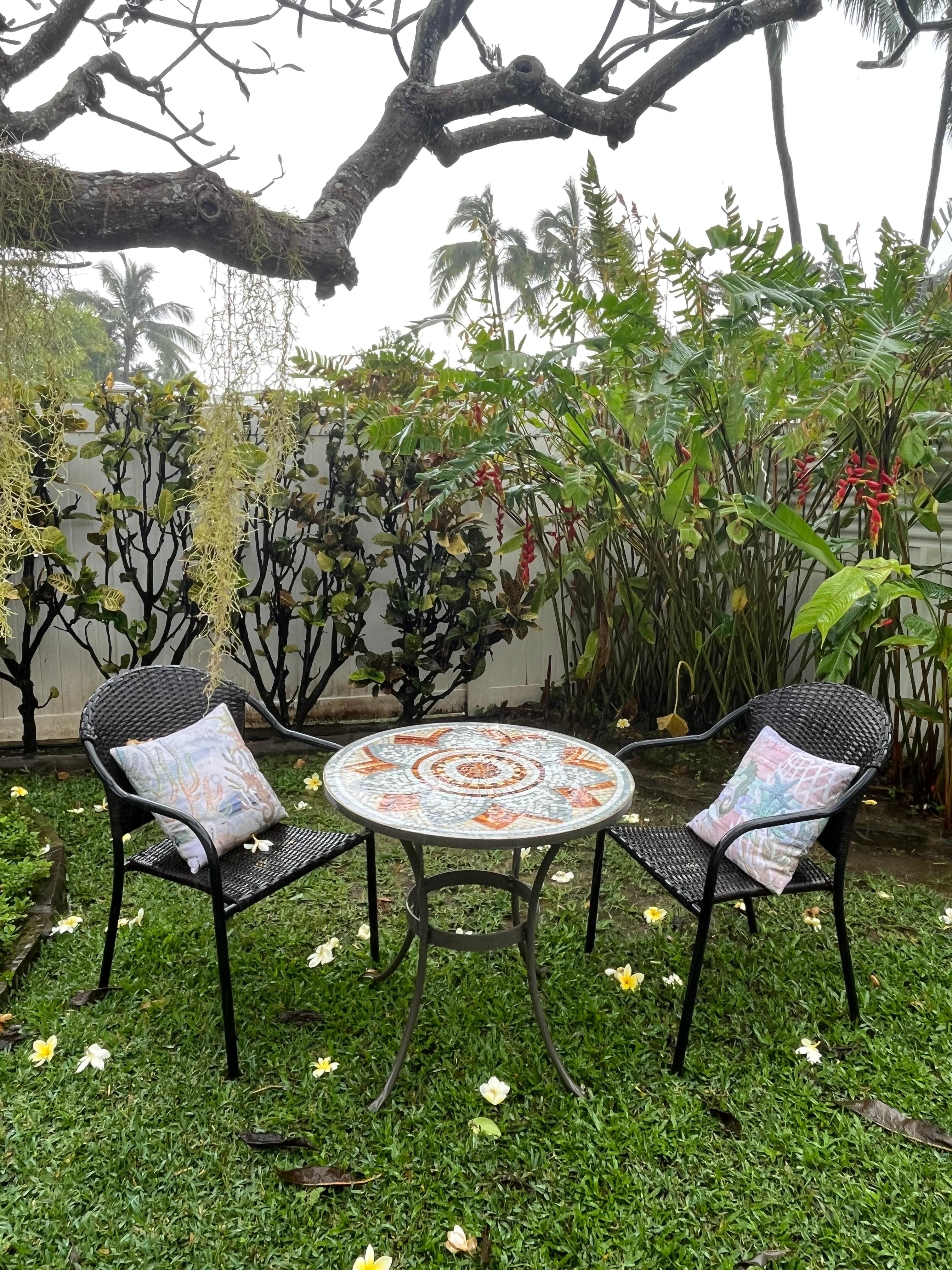 The bistro set still looks inviting even after a rainstorm, showered with plumeria blossoms.