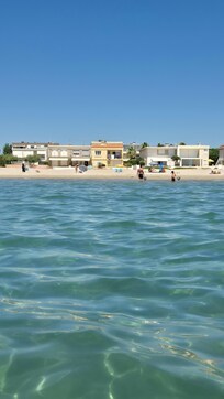 Blick vom Meer aus zum Haus am Strand. Es ist das Gelbe in der Mitte. Die Wohnung befindet sich auf der RĂŒckseite zur StraĂe hin.