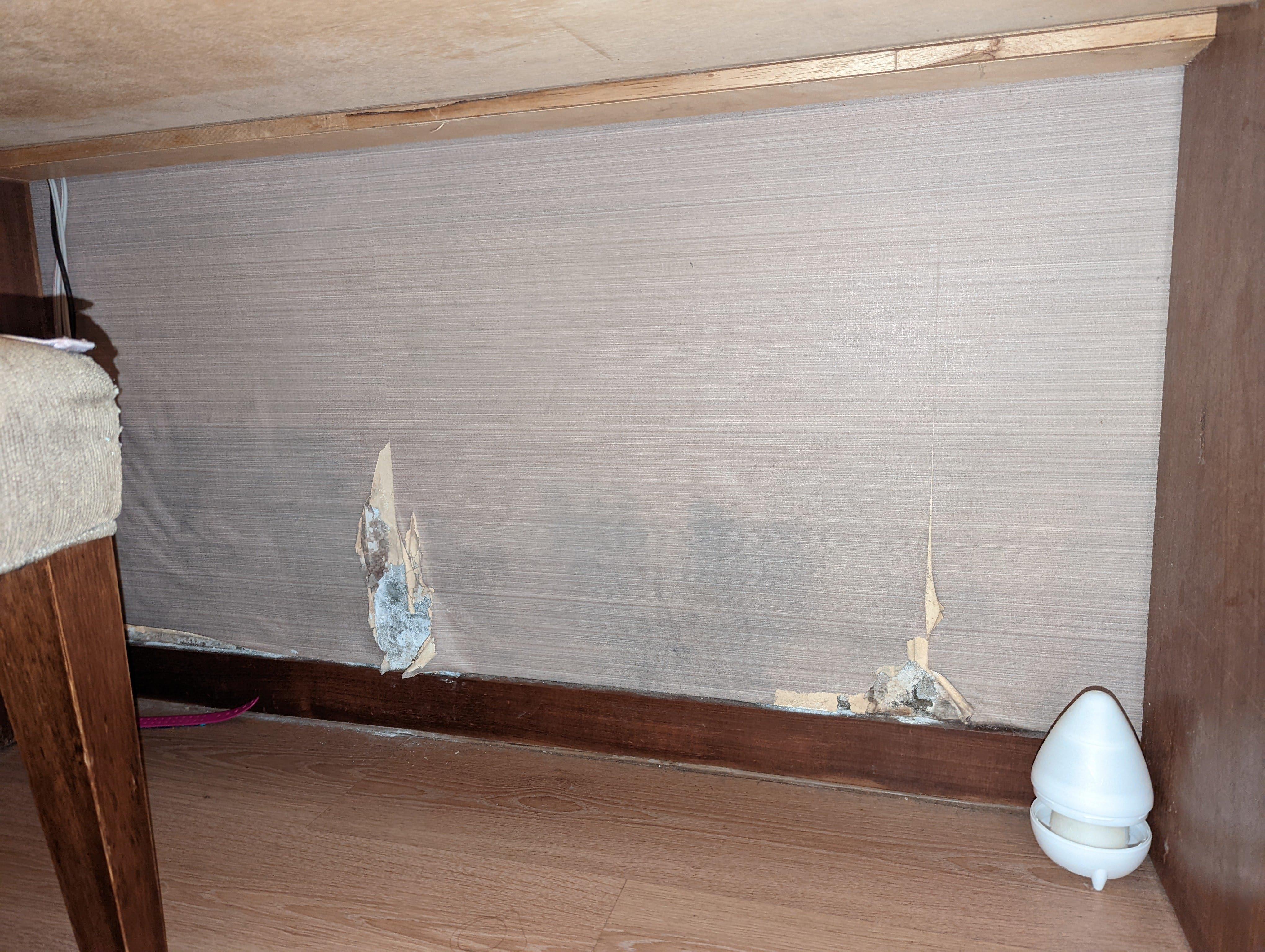 Damaged wall under desk