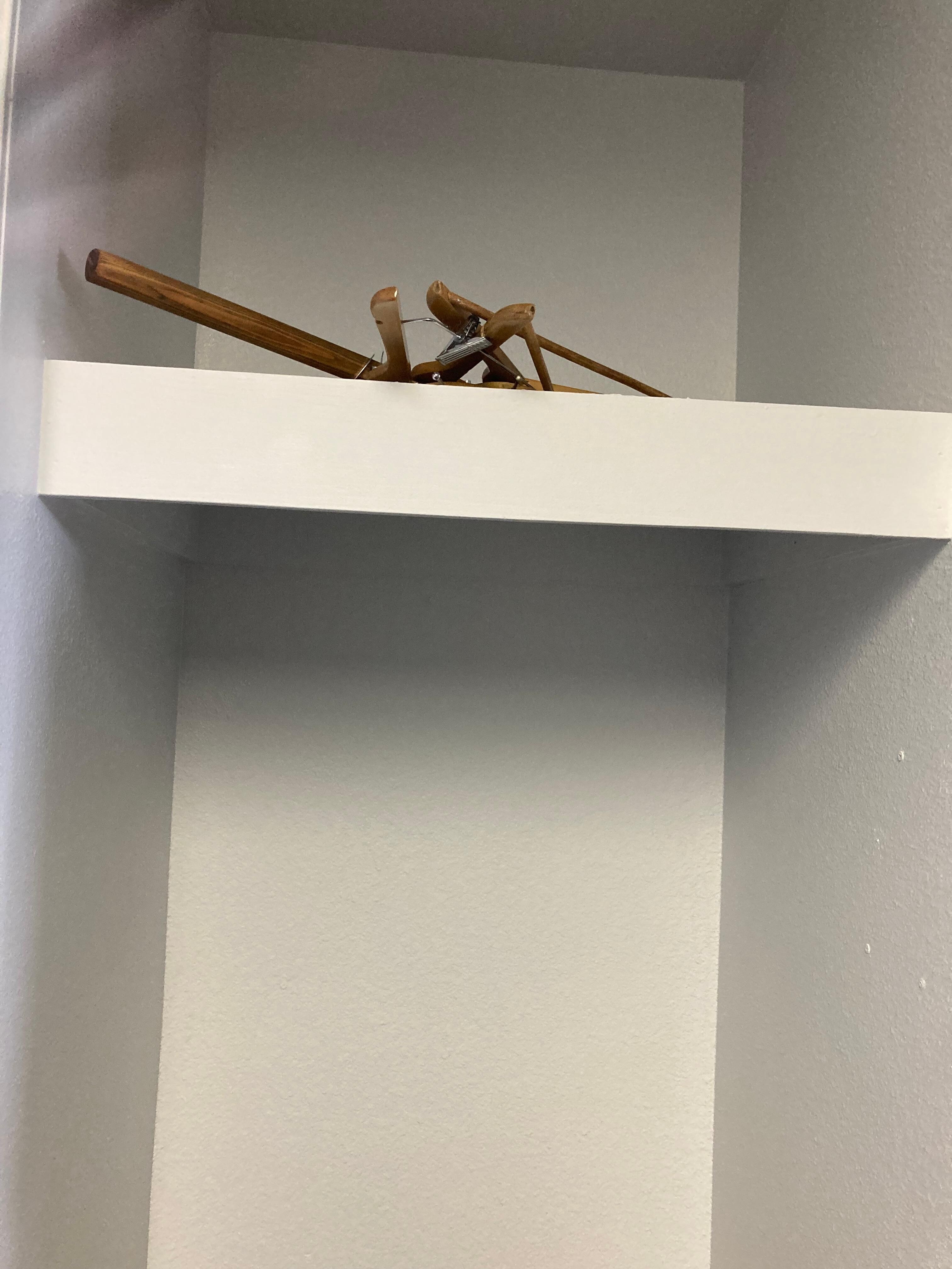No clothes rod and hangers thrown on shelf. 