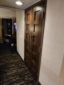 Hallway to bedroom, closet for clothes/iron board/iron, suitcase rack.