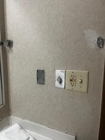 No towel bar, metal protruding from bracket and another metal thing on the wall with sharp edges (very left of switches)