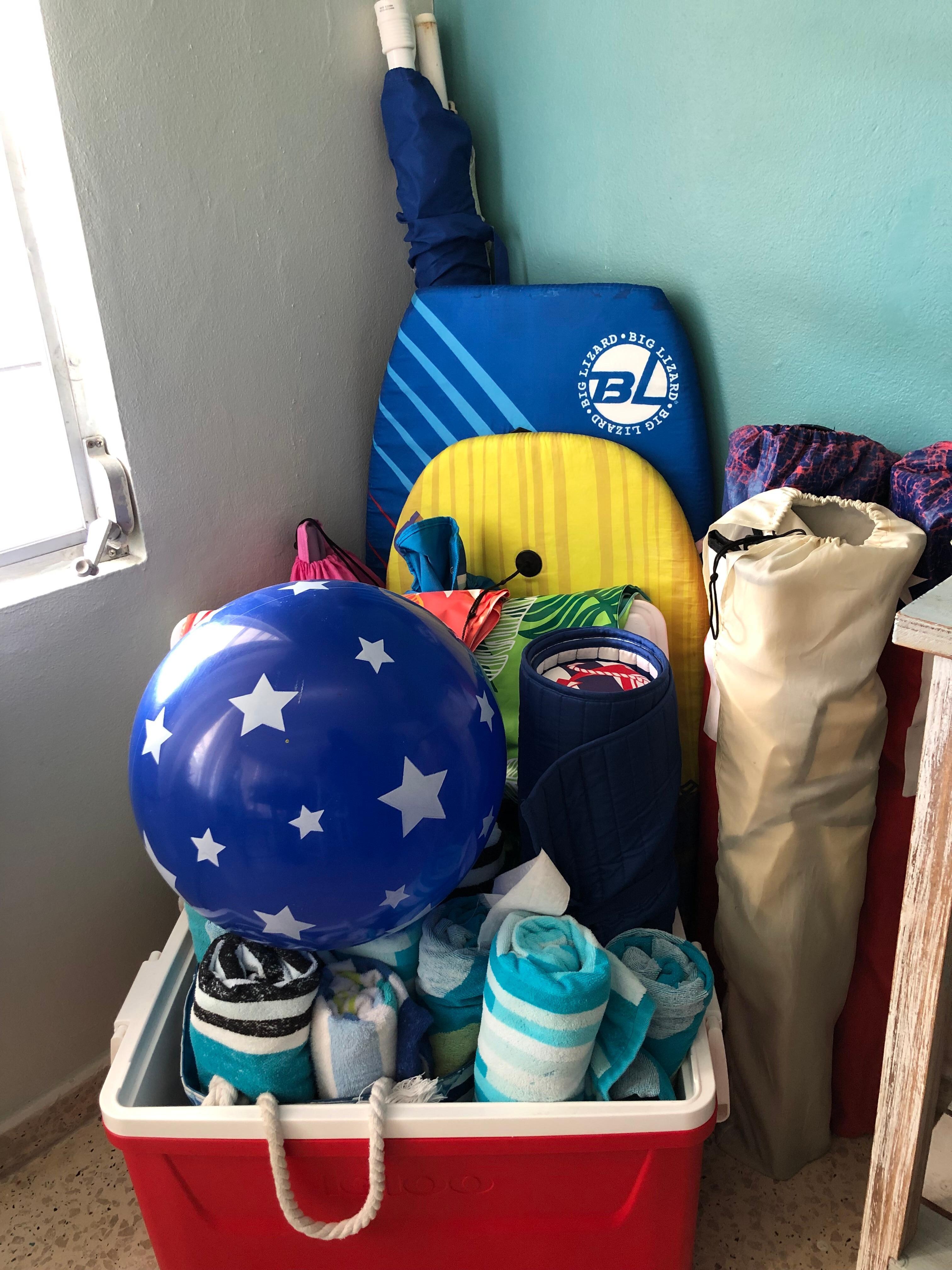 Beach gear for guests' use - towels, chairs, boogie boards, umbrella, and ice chest.