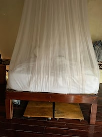 Cama com mosquiteiro e ventilador.