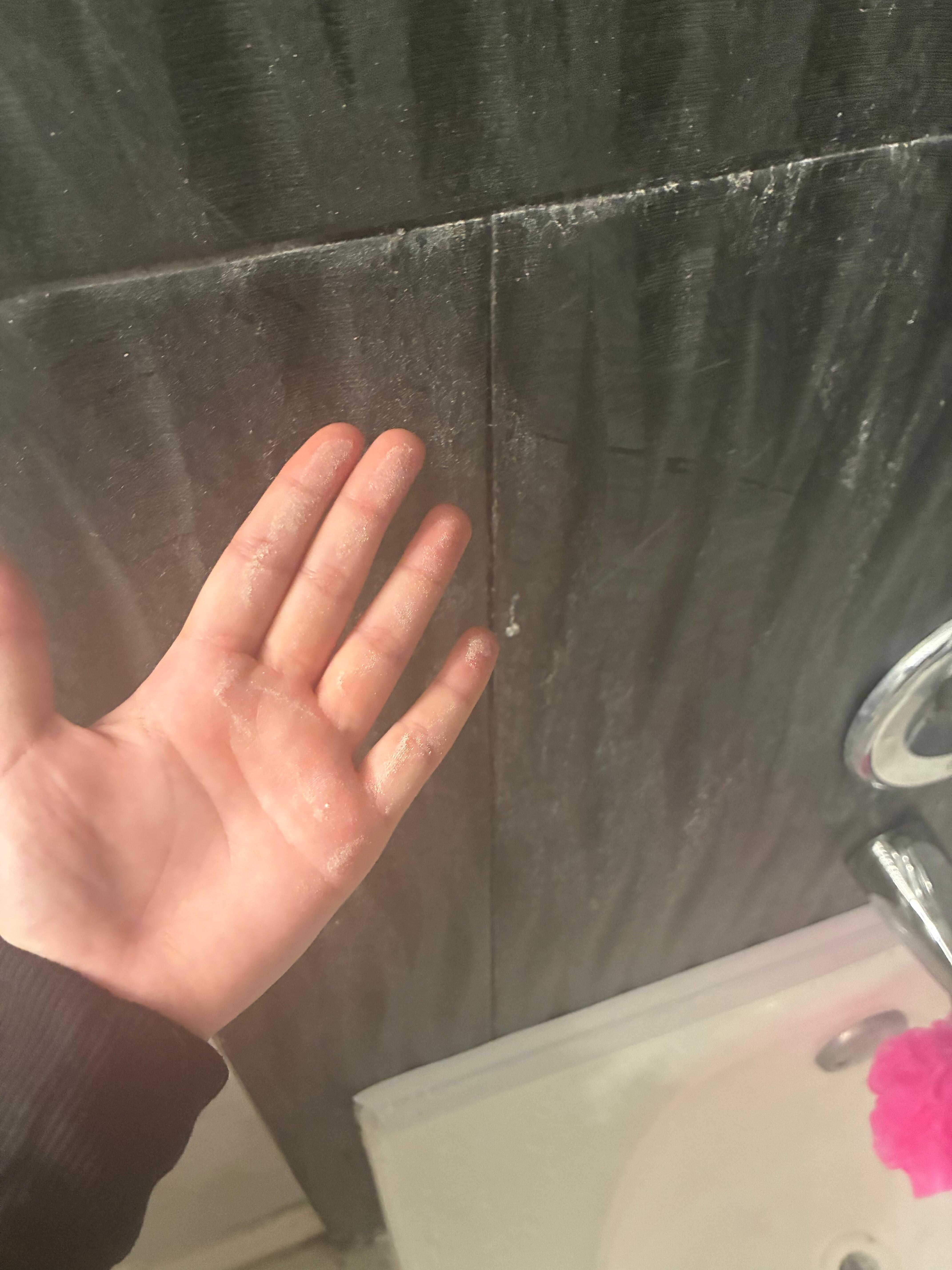 Paint particles and chemical debris on the shower walls and tub 