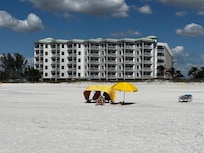 From ocean looking back at cabana and umbrella with Sunset Villas