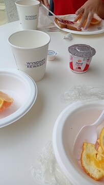 En el desayuno hay trozos de naranjas, tres opciones de cereales, leche, café y algo de pan.