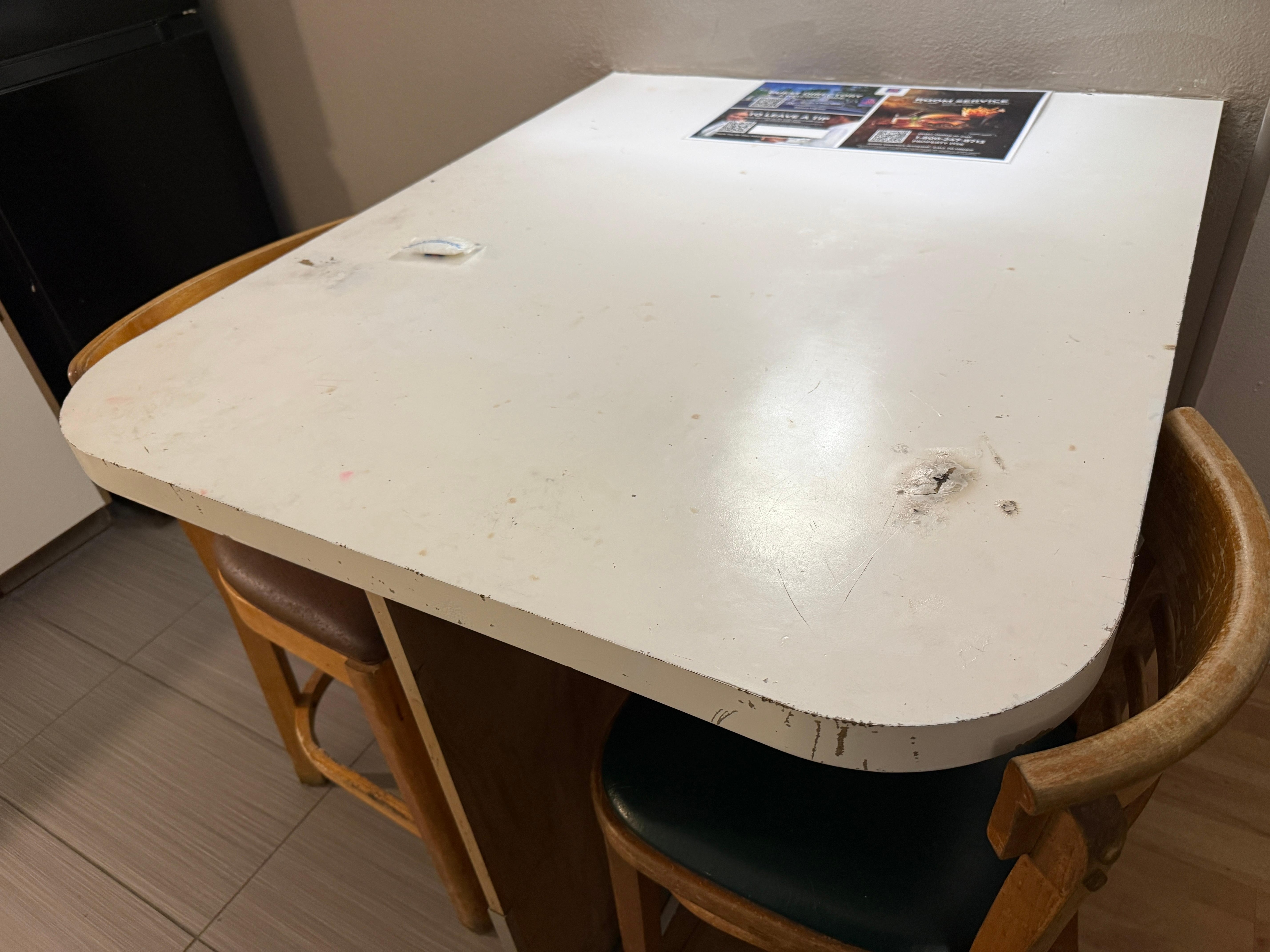 Table in the “non-smoking” room that is covered with cigarette burns. 