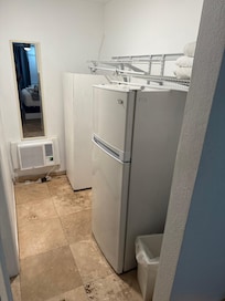 Fridge in closet holding up closet shelf with dirty spoons on top