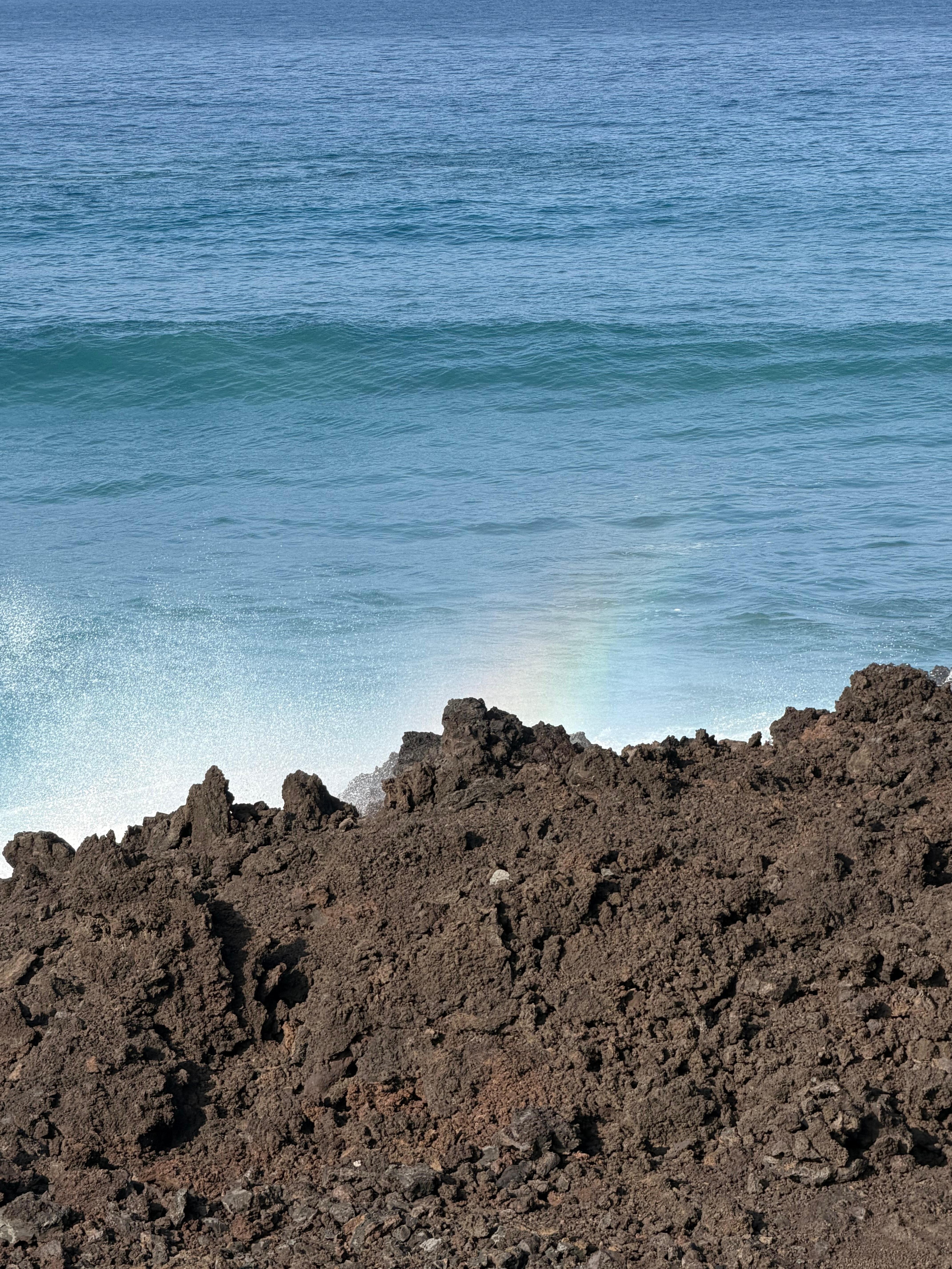 From the balcony - waves crashing against the lava rock wall and creating a rainbow. 