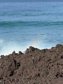 From the balcony - waves crashing against the lava rock wall and creating a rainbow.