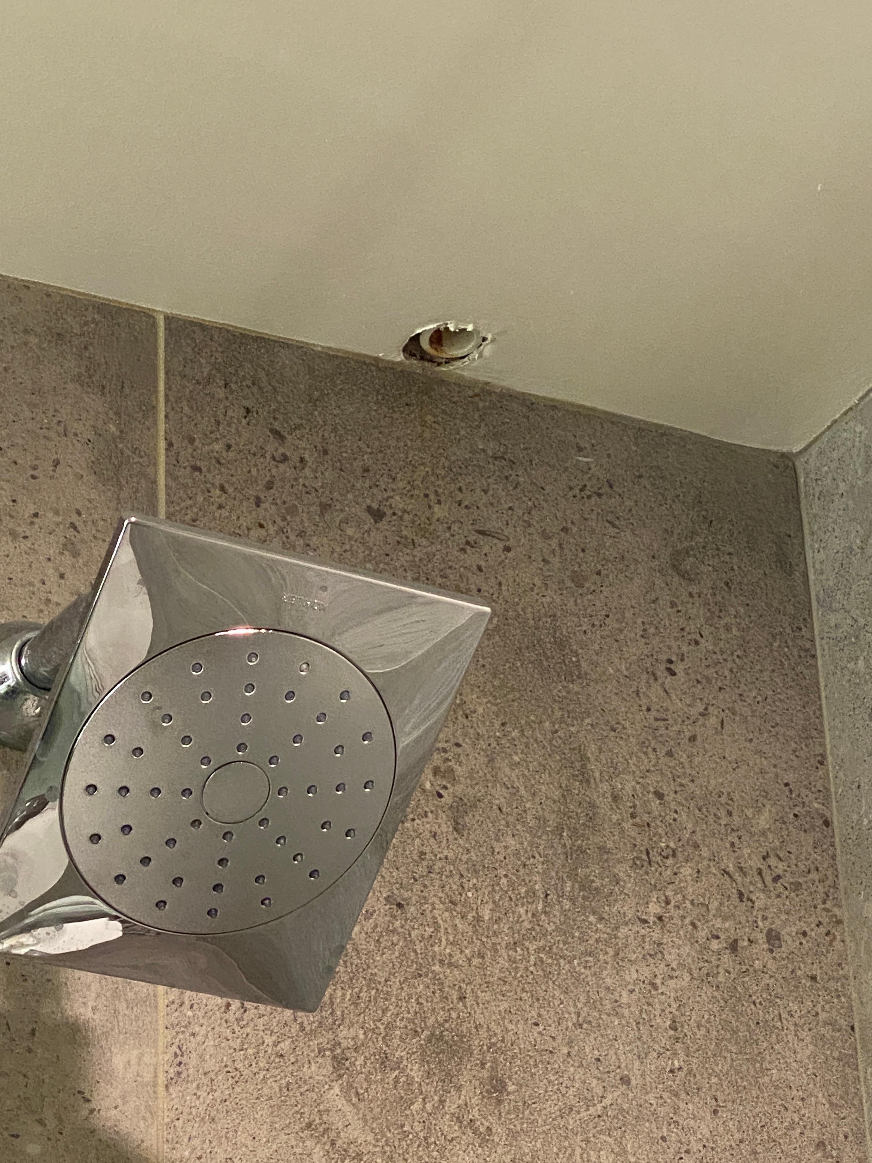 Hole in shower ceiling with a weird plastic pipe hanging out