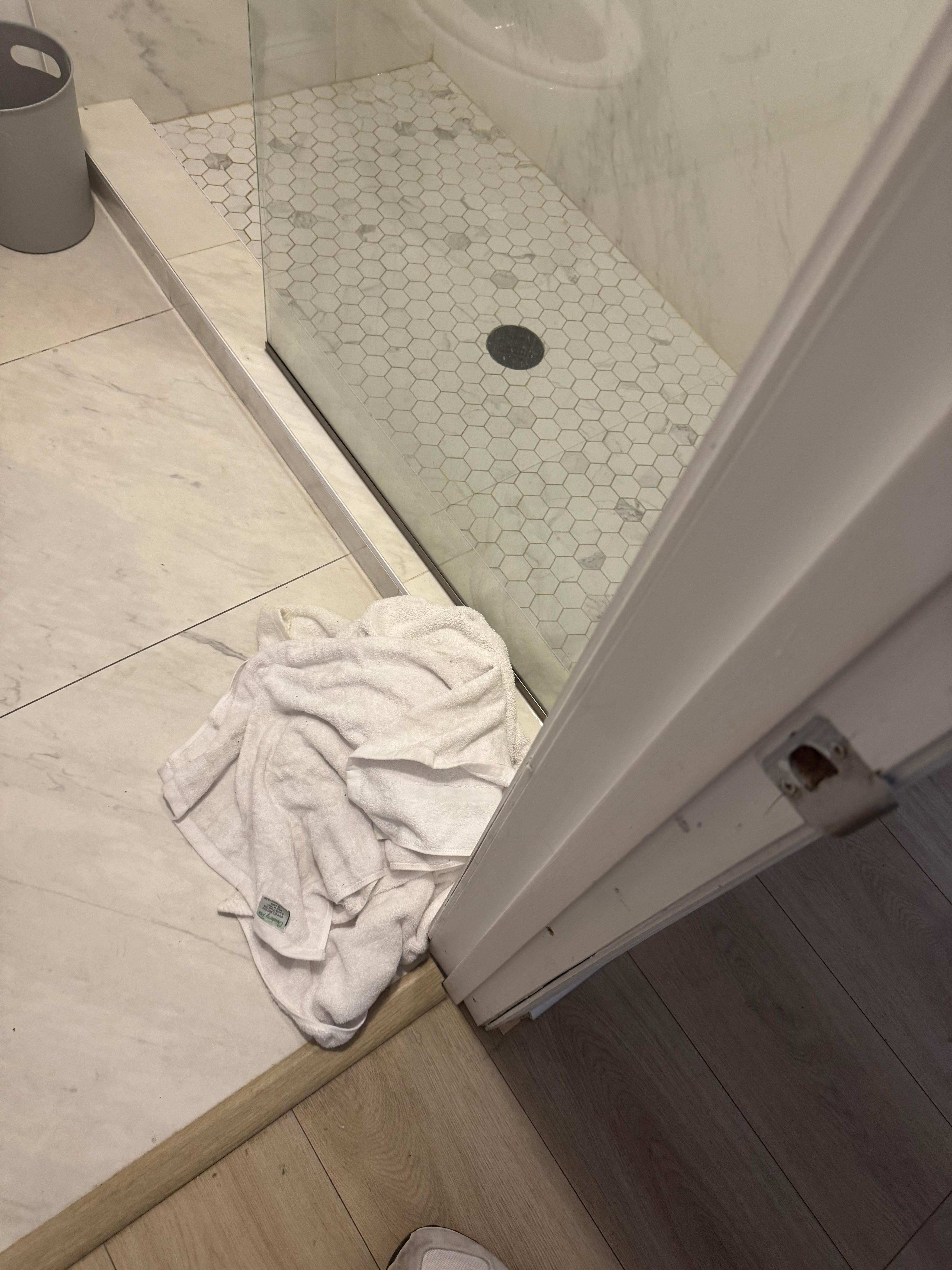 Dirty wet towels balled up on bathroom floor.  