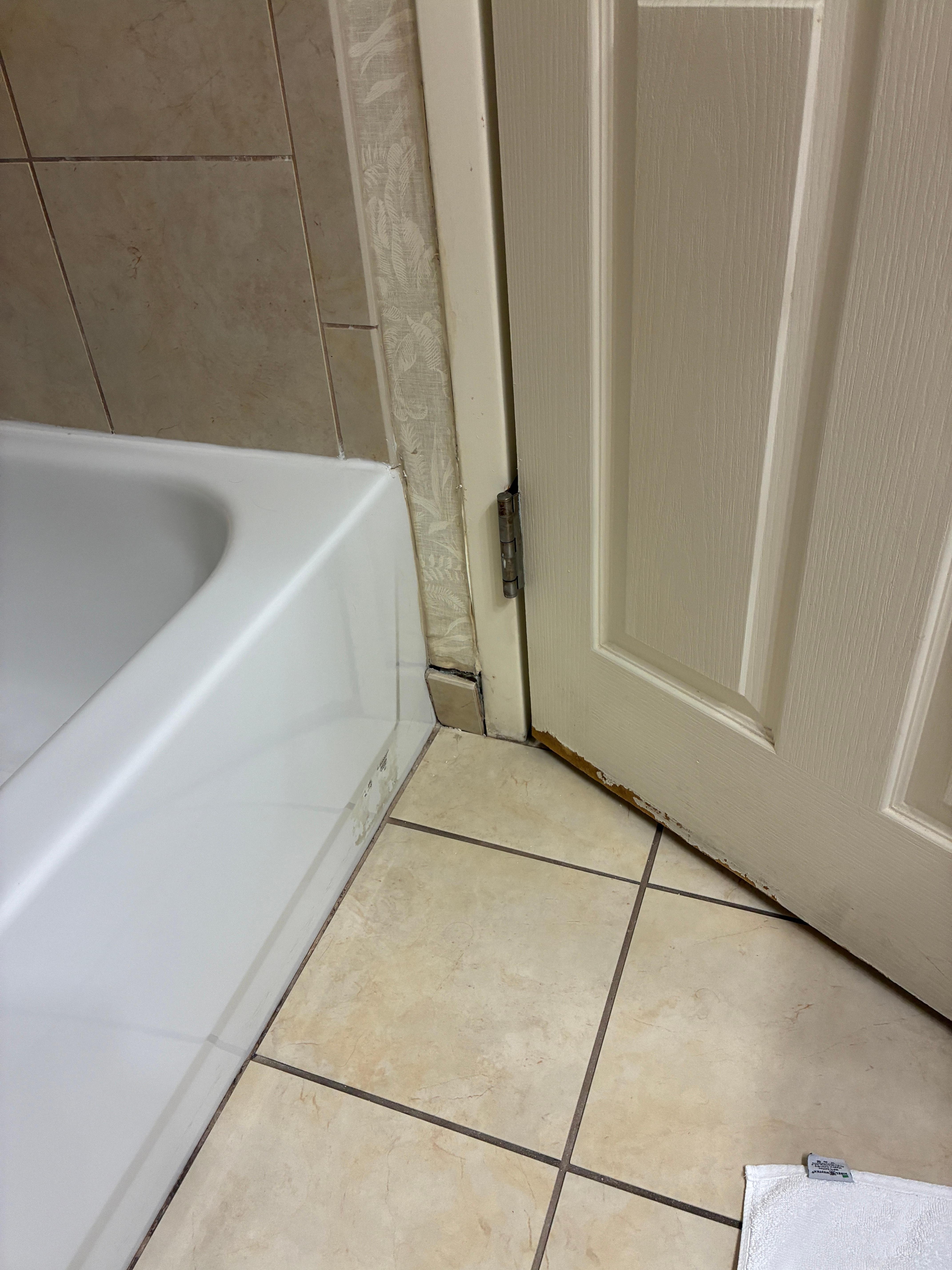Tile falling off the wall in the bathroom with black mold behind it