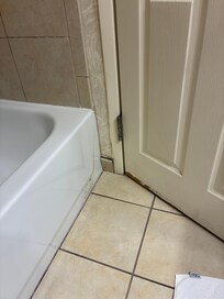 Tile falling off the wall in the bathroom with black mold behind it