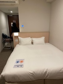 A strange orientation of bed with door at the back and side is wall mounted TV