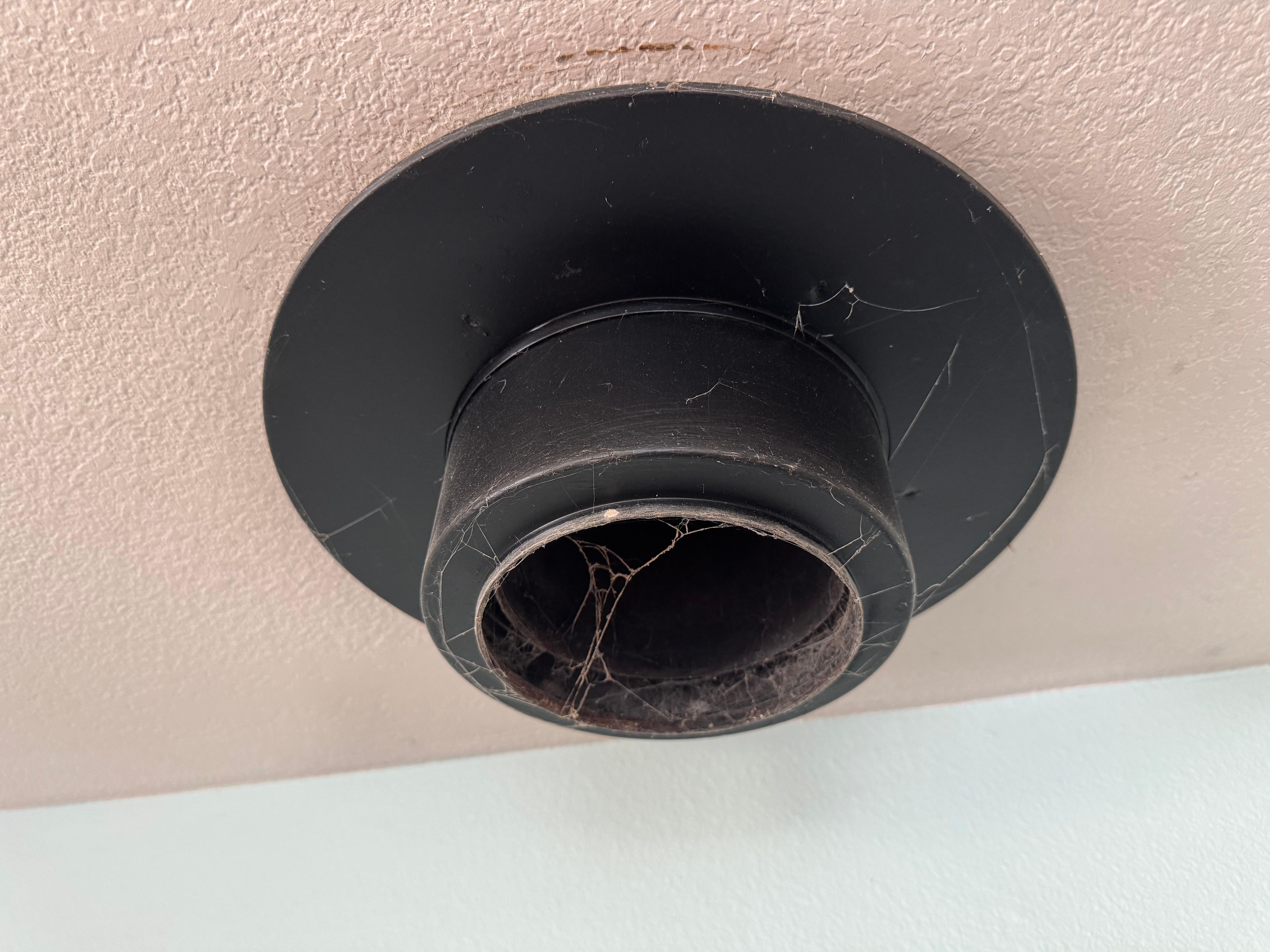 Closeup of the hole in the ceiling where a stove chimney used to be, with cobwebs.  I'm sure this will be removed and the ceiling fixed eventually