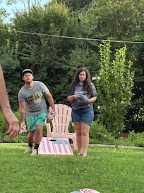 Family enjoying a game of cornhole in the beautiful yard