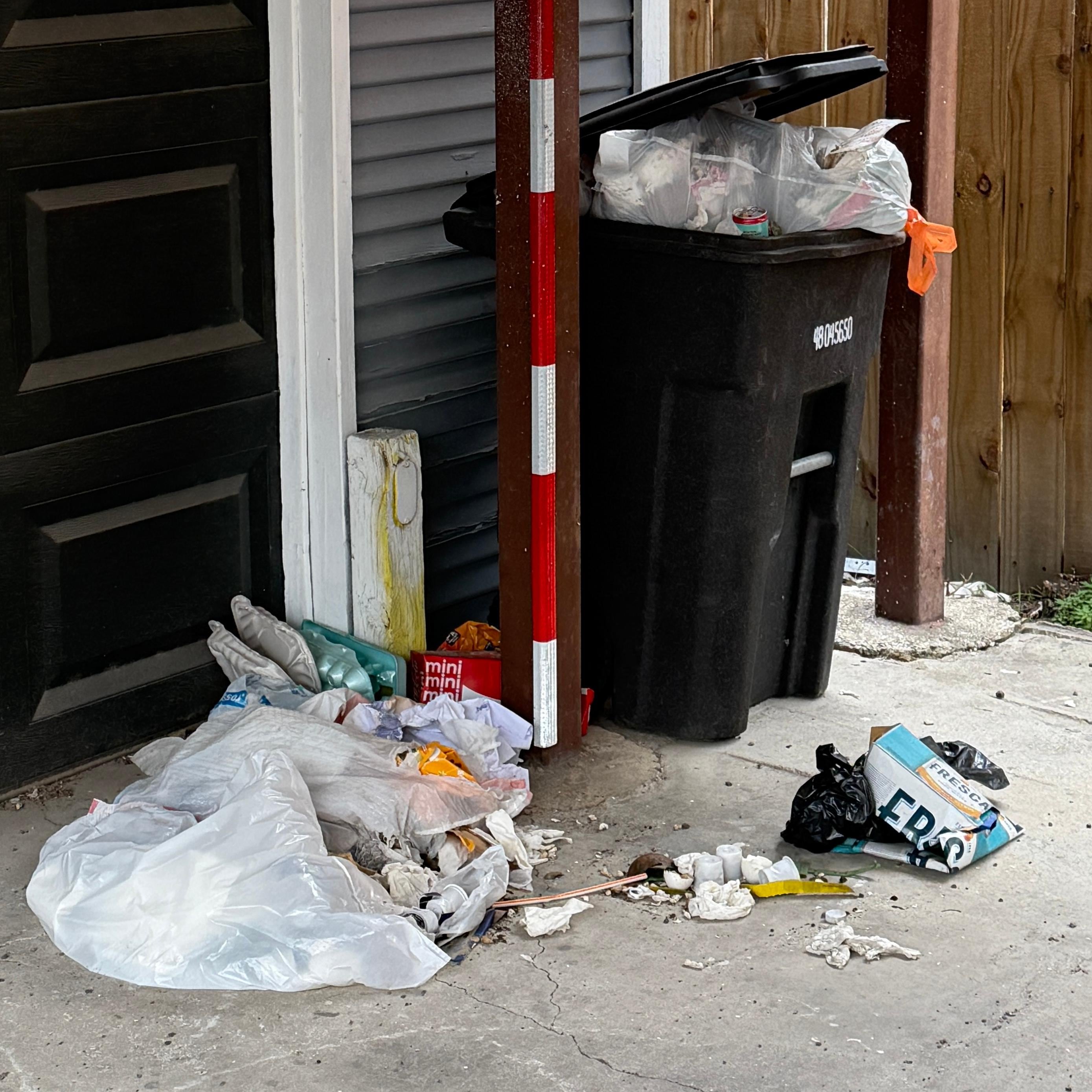 Overflowing trash in the carport from the previous guests.