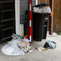 Overflowing trash in the carport from the previous guests.