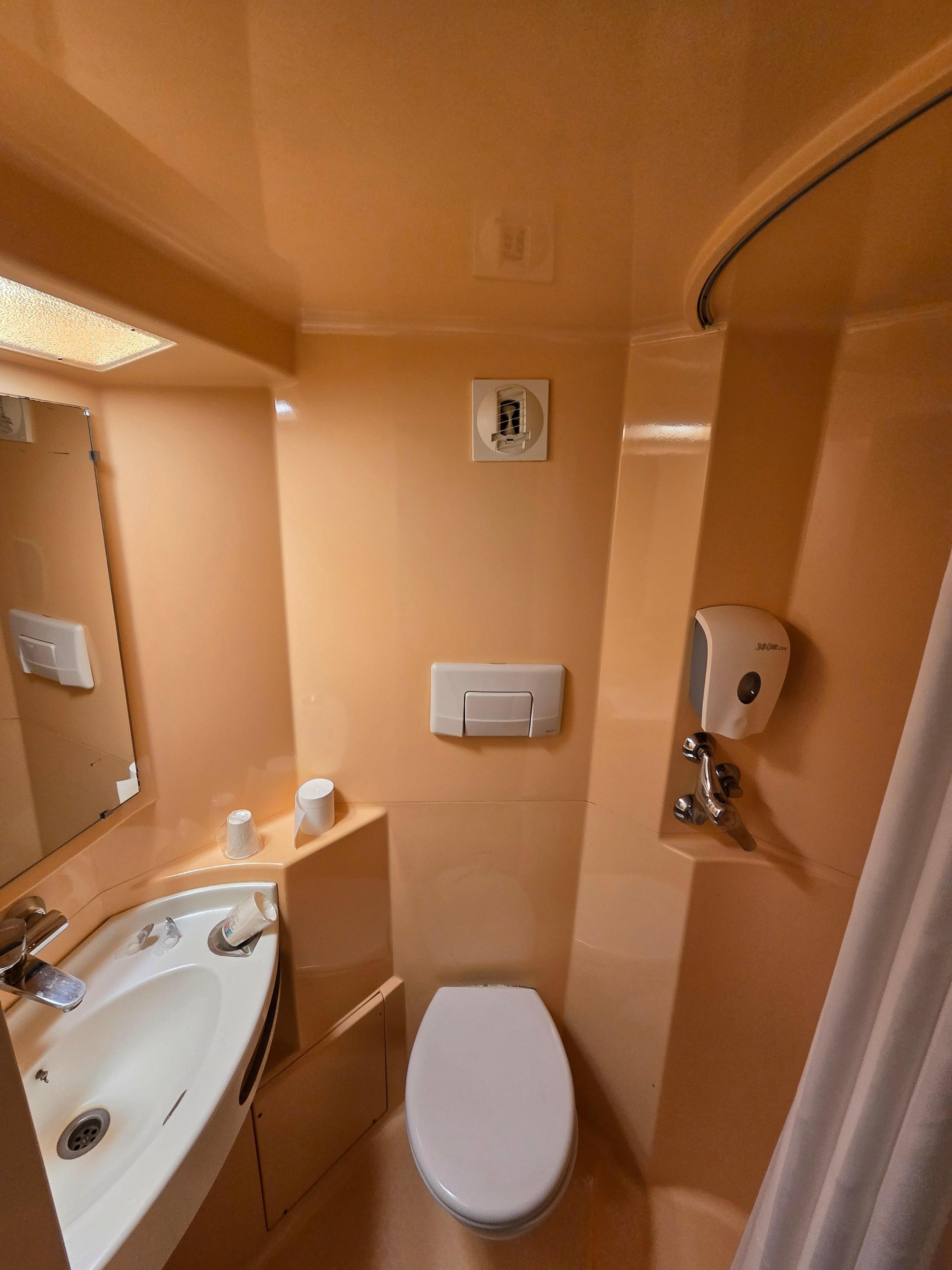 Plastic bathroom with no towels and prone to floor flooding