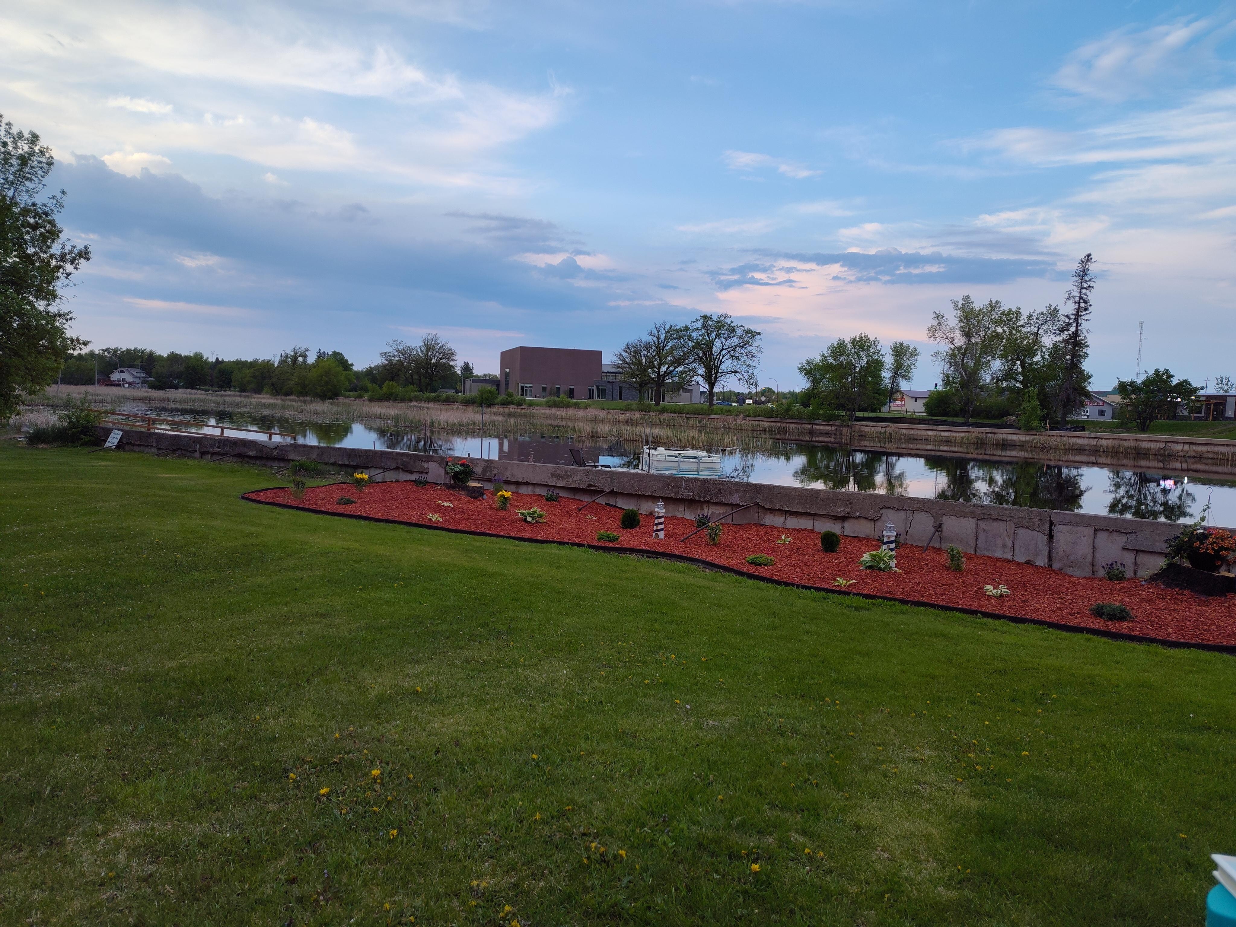 Long view of lawn, landscaping, and river from the backyard chairs.