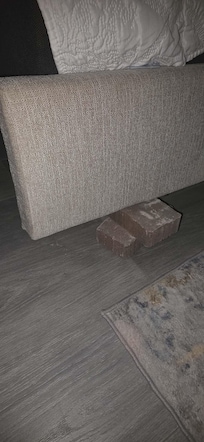 Broken bedframe making the bed uneven. Used brick to try and level bed