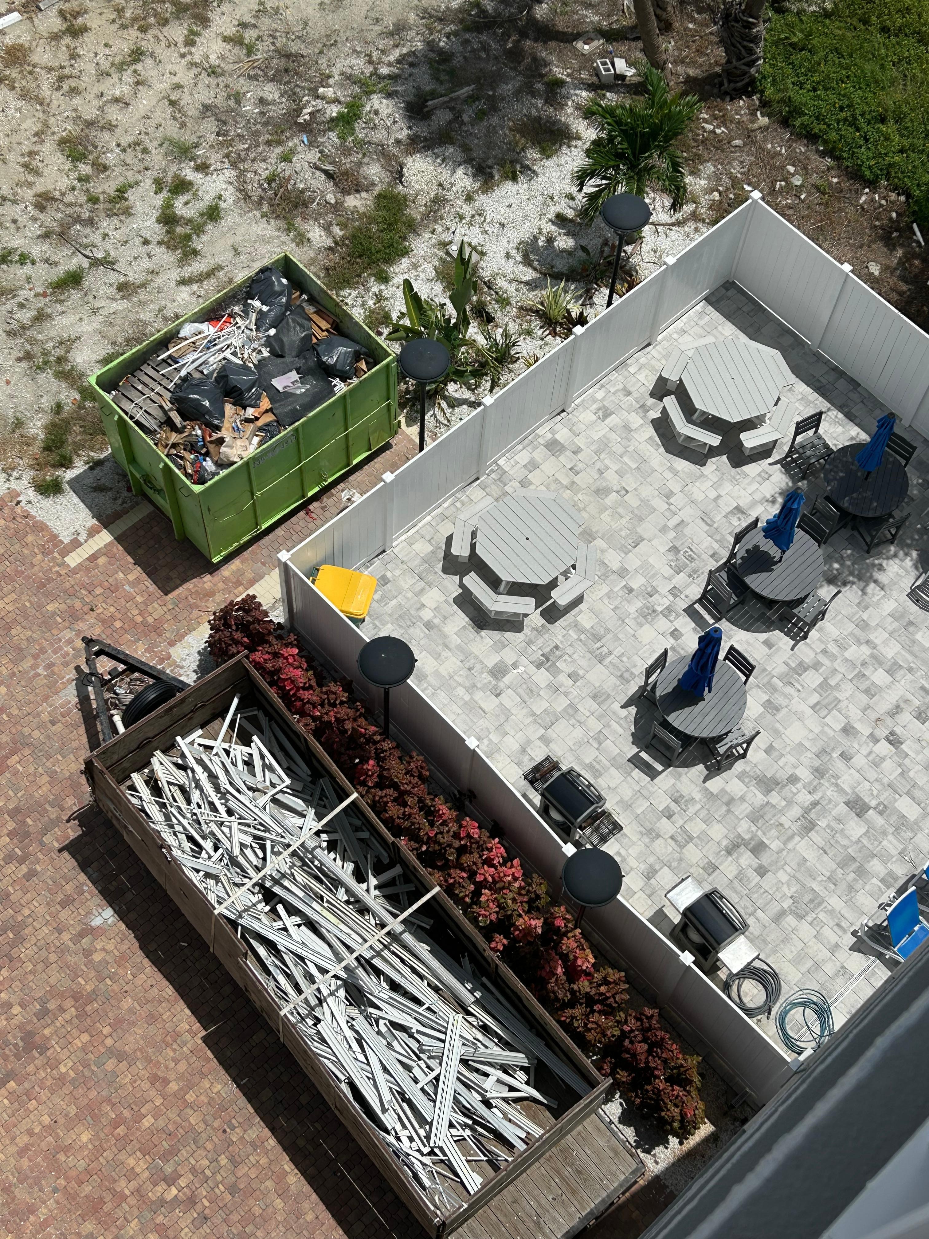 Dumpster just on the other side of pool fence where workers threw old windows.  