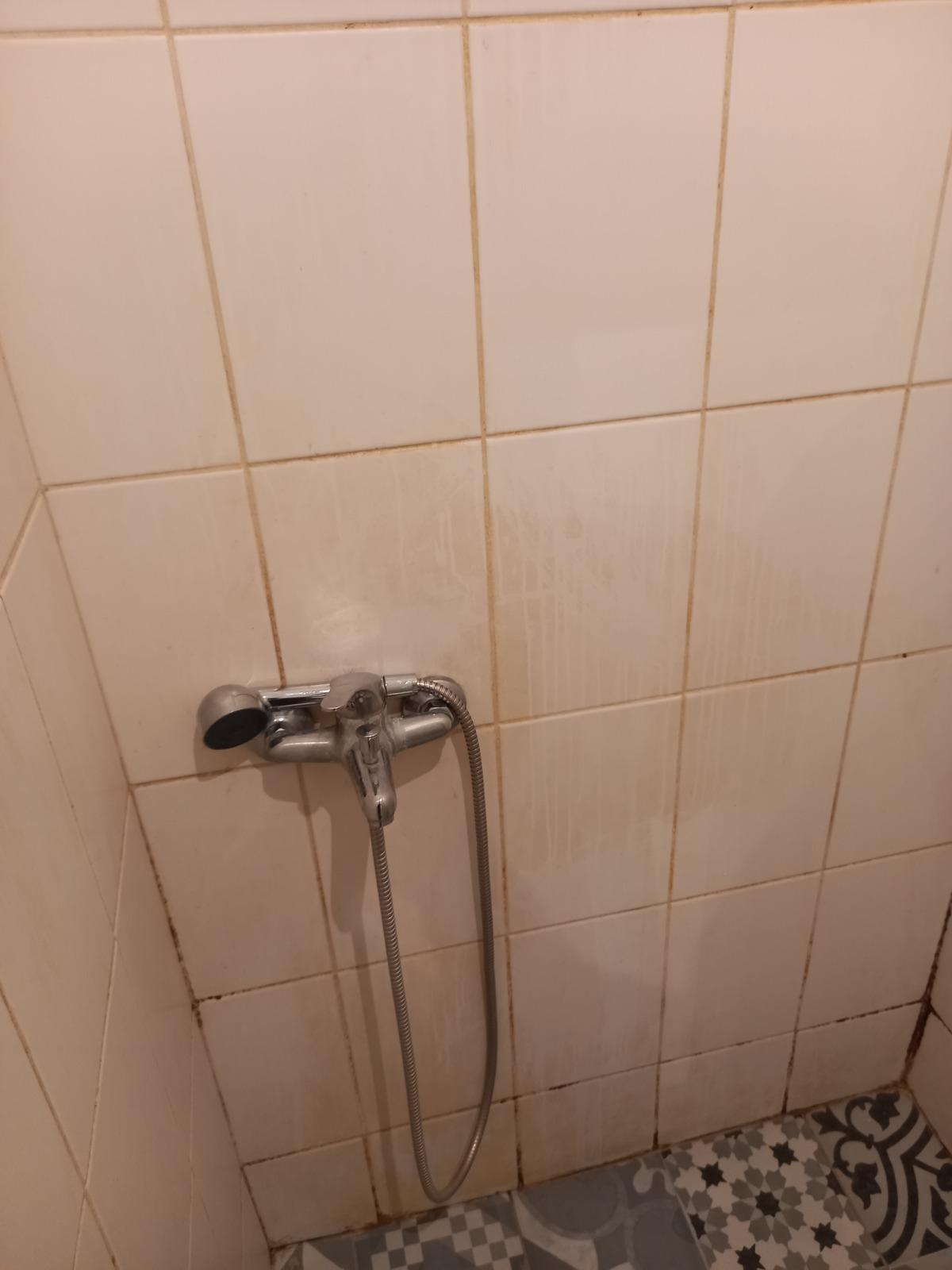 Filthy shower with broken shower head