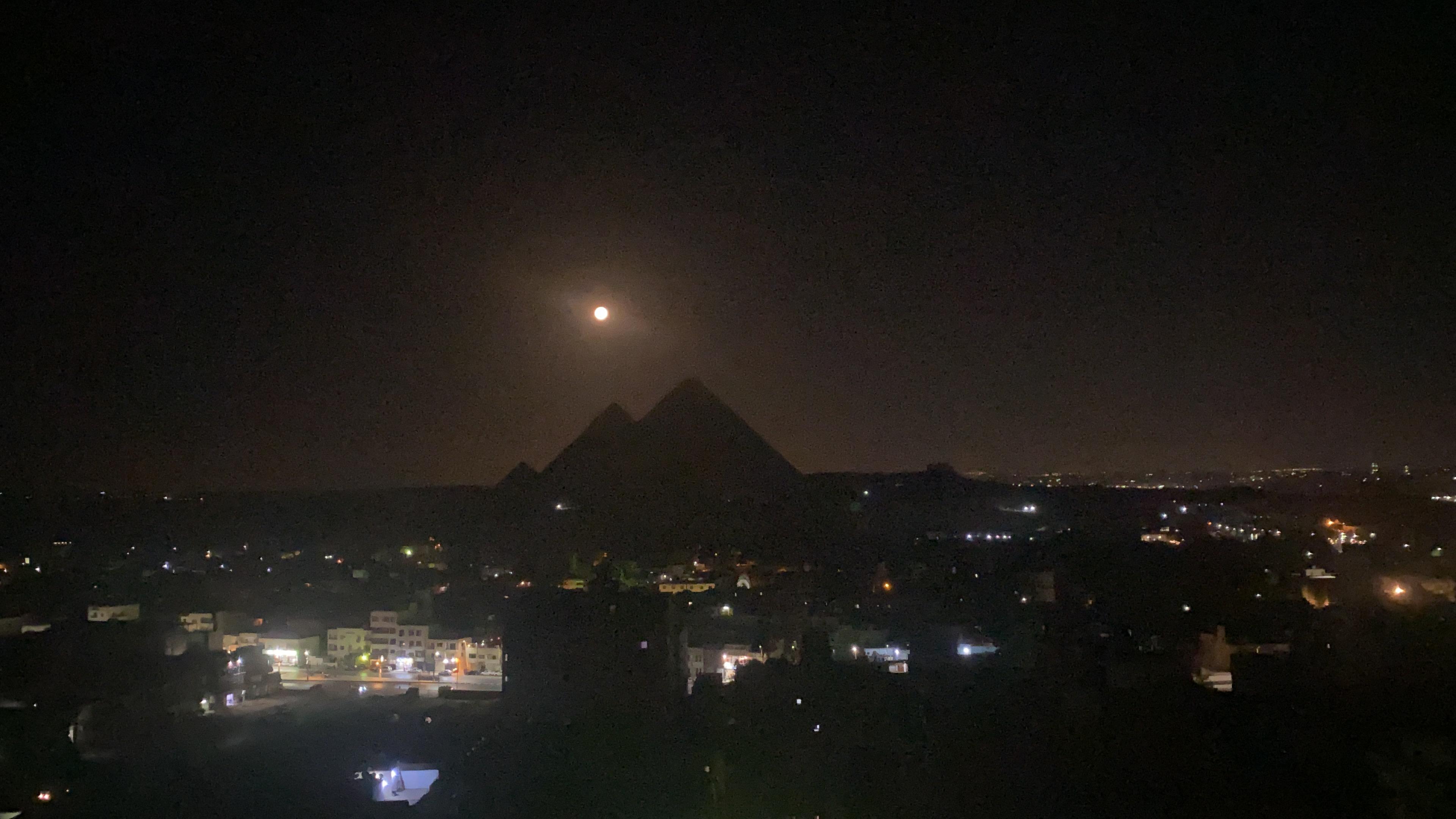 Moon over pyramids at night from rooftop 