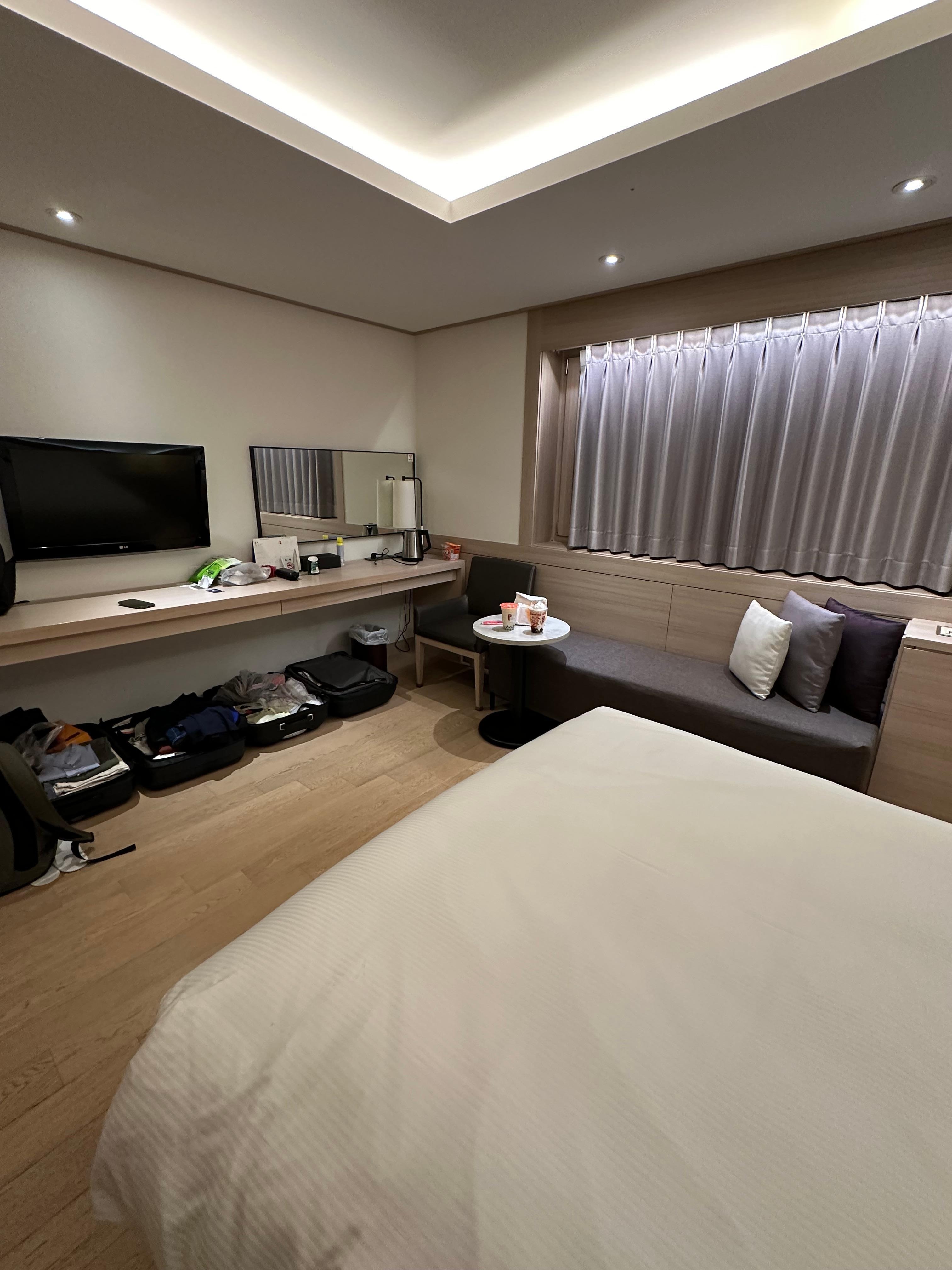 God plass i rommet med åpen koffert under bord langs veggen og en liten sofa