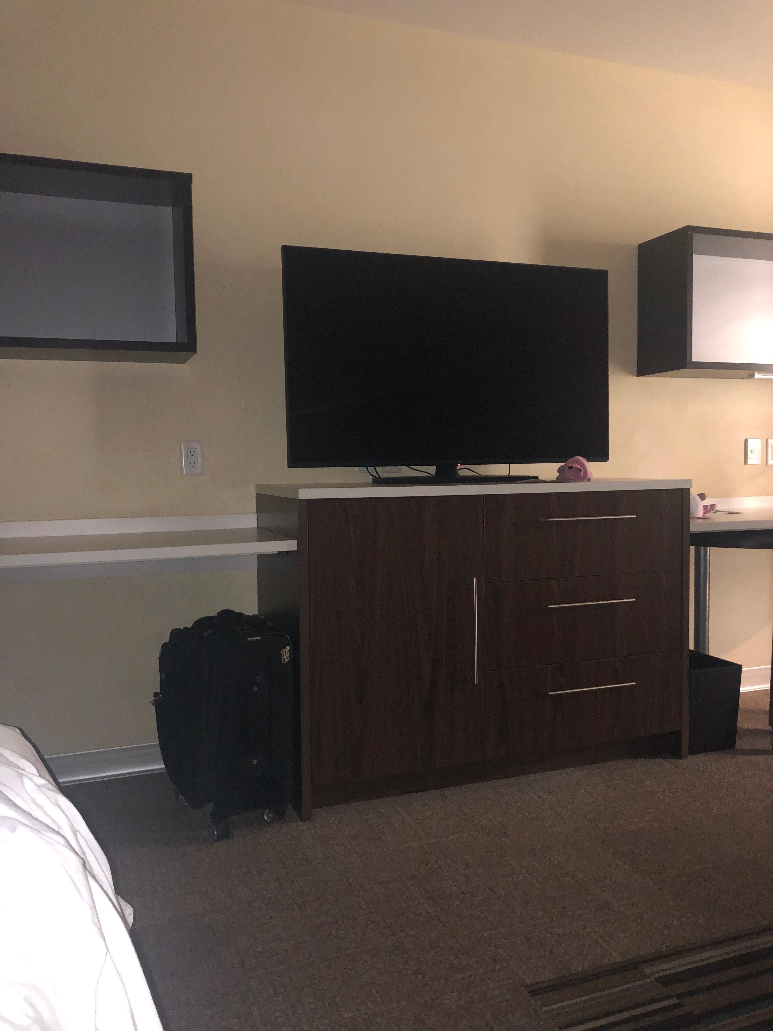 Medium size Flatscreen TV above a cabinet with a safe in it.