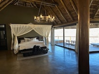 Bed, with mosquito nets, looks out over deck, with sun loungers and private hot tub