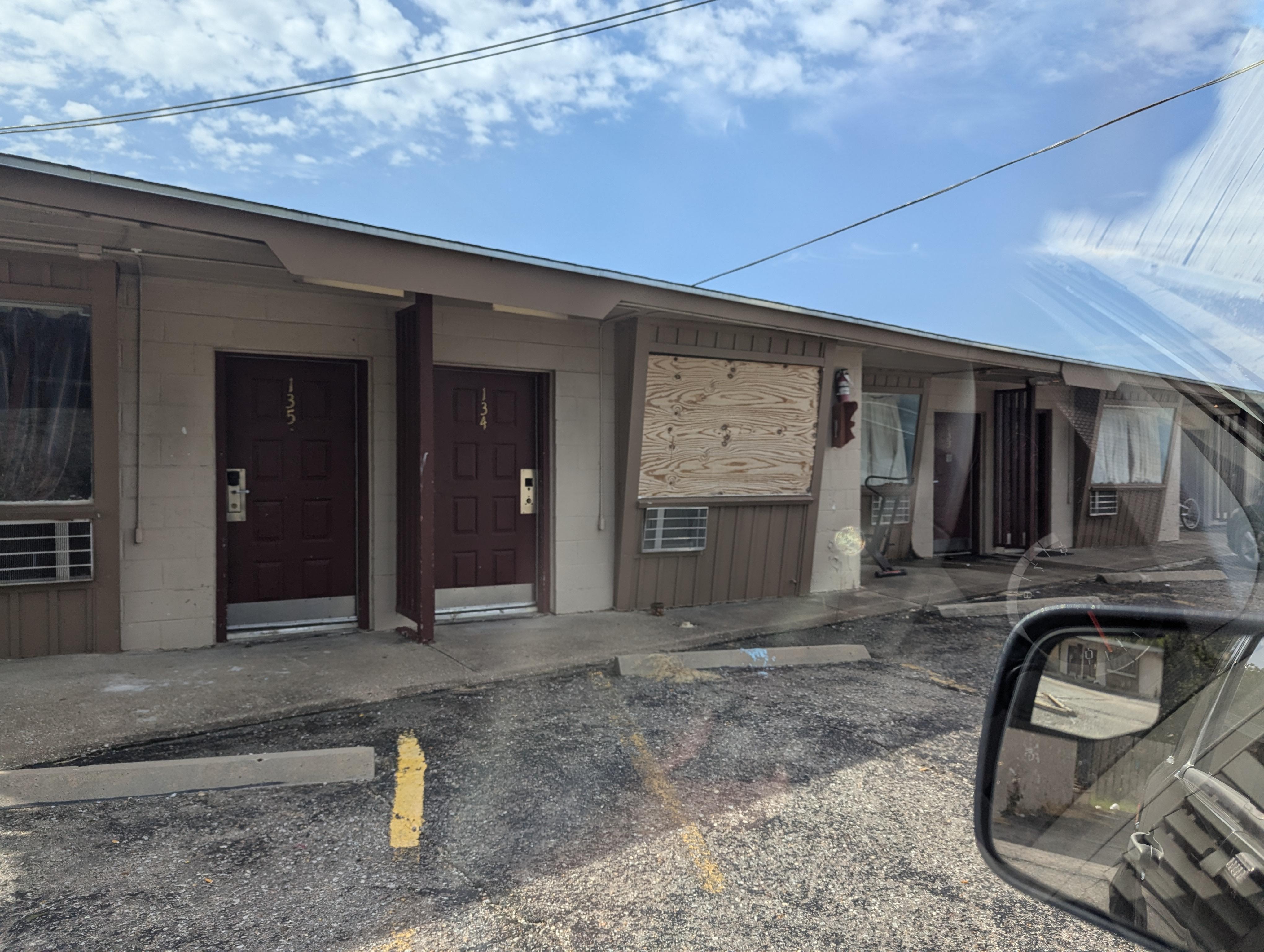 Boarded up windows. Trash outside.