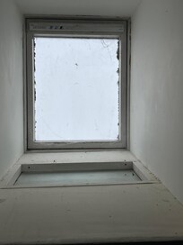 Bathroom skylight and sloped walls with dead bugs and cobwebs