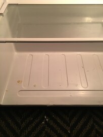 Refrigerator complete with food on carpet.