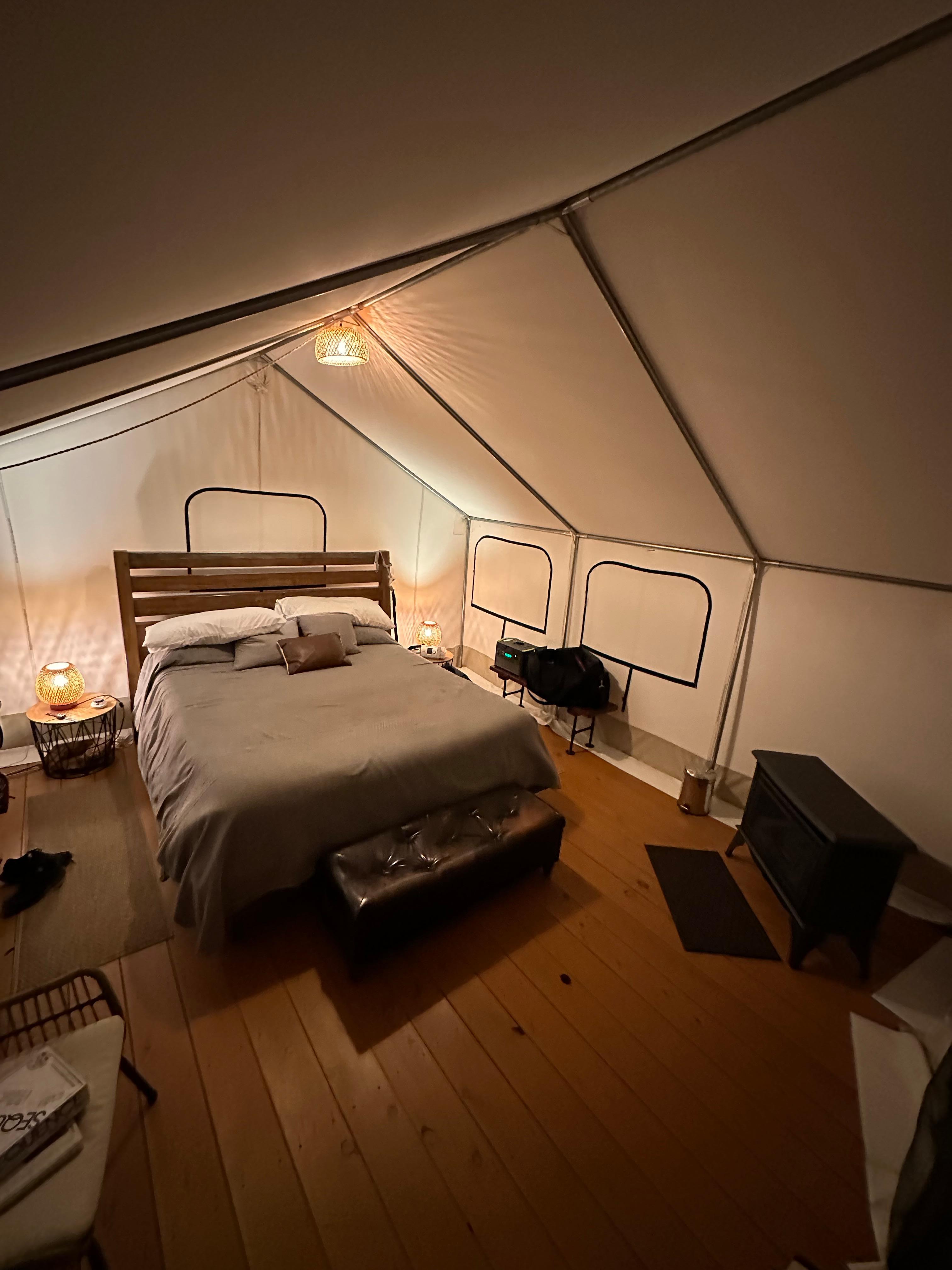 Well-stocked tent with hardwood floors and rugs, ample seating, comfortable bedding, and even an electric blanket and indoor fireplace