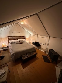 Well-stocked tent with hardwood floors and rugs, ample seating, comfortable bedding, and even an electric blanket and indoor fireplace