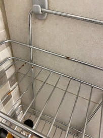 Shower in need of cleaning. Here is the rusted shelf in the shower.